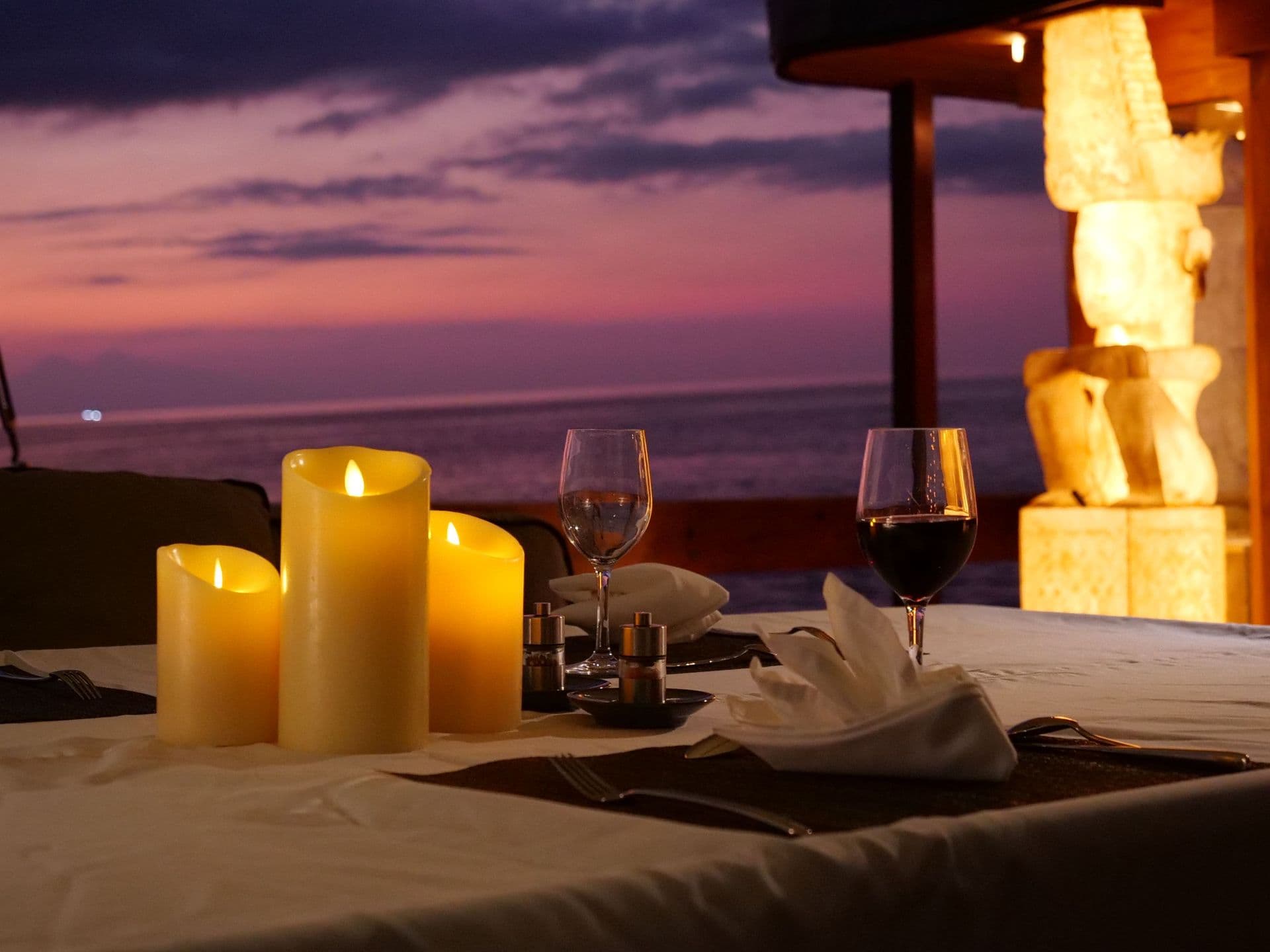 dining table setting on the deck, beautiful sunset, purple sky, candles, glass