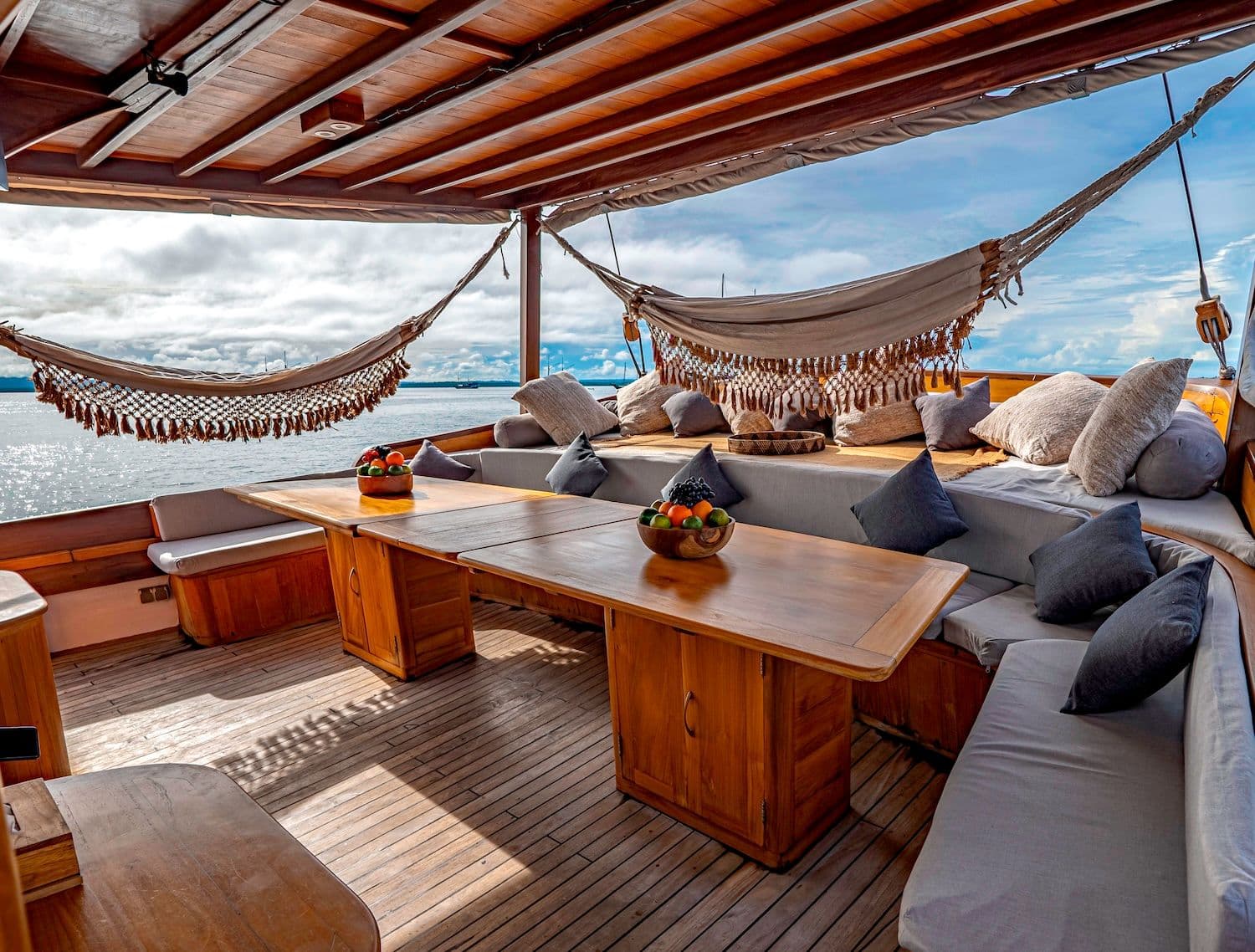 relax spot at anne bonny boat, wooden exterior, crochet curtains, gray sofa, wooden table, blue sky on the background