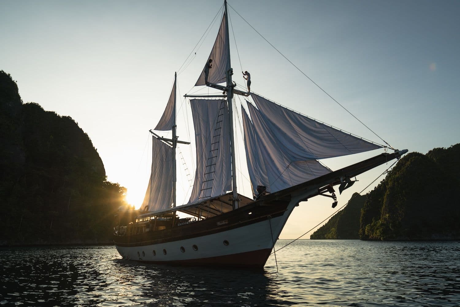 anne bonny boat, white big sails, wooden boat exterior, sunrise view on the background