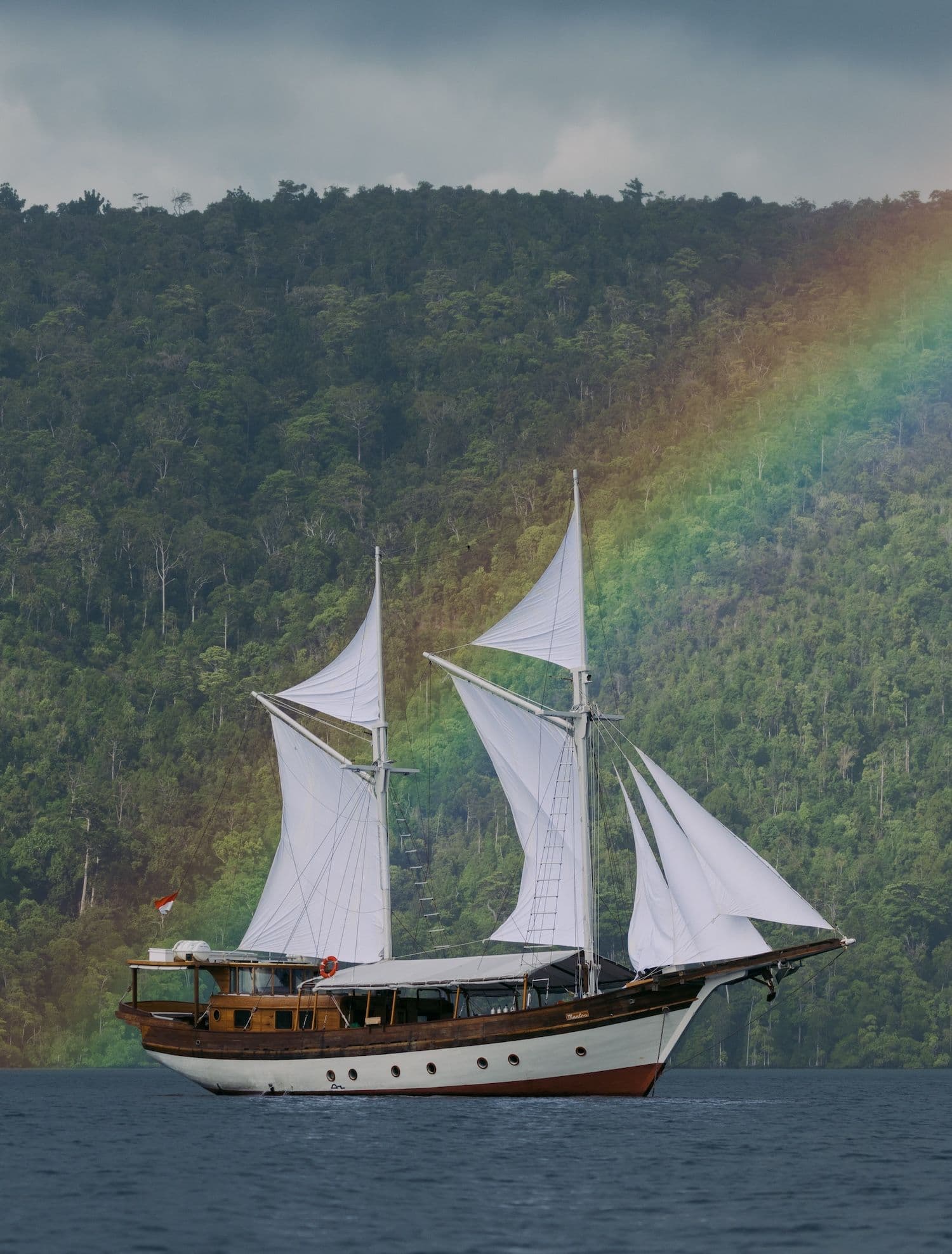 anne bonny boat, white big sails, wooden boat exterior, rainbow view on the background