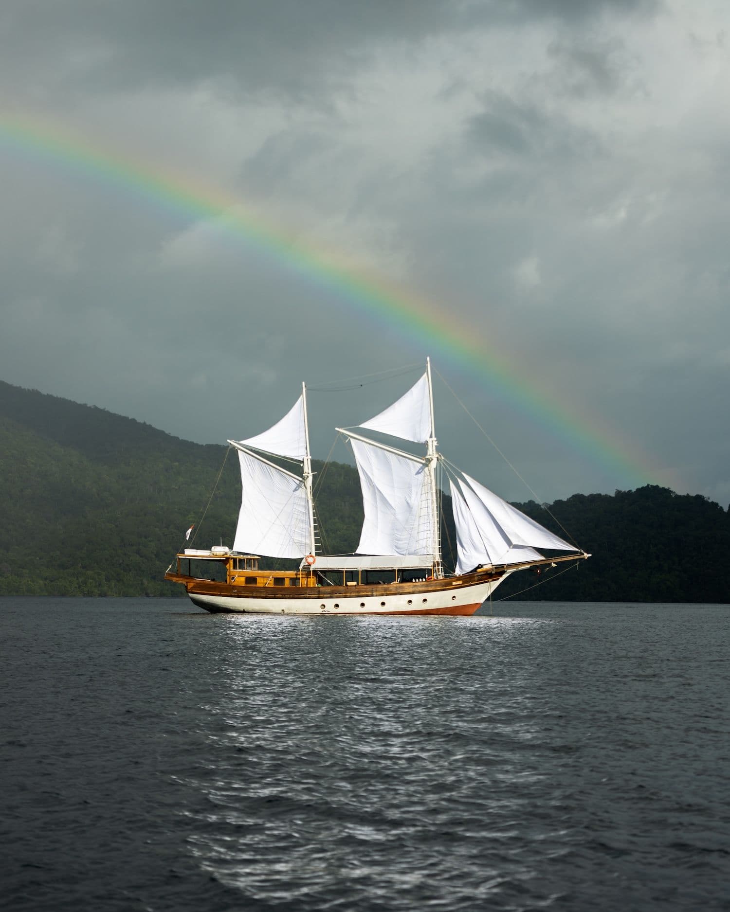 anne bonny boat, white sail, rainbow on the background, cloudy