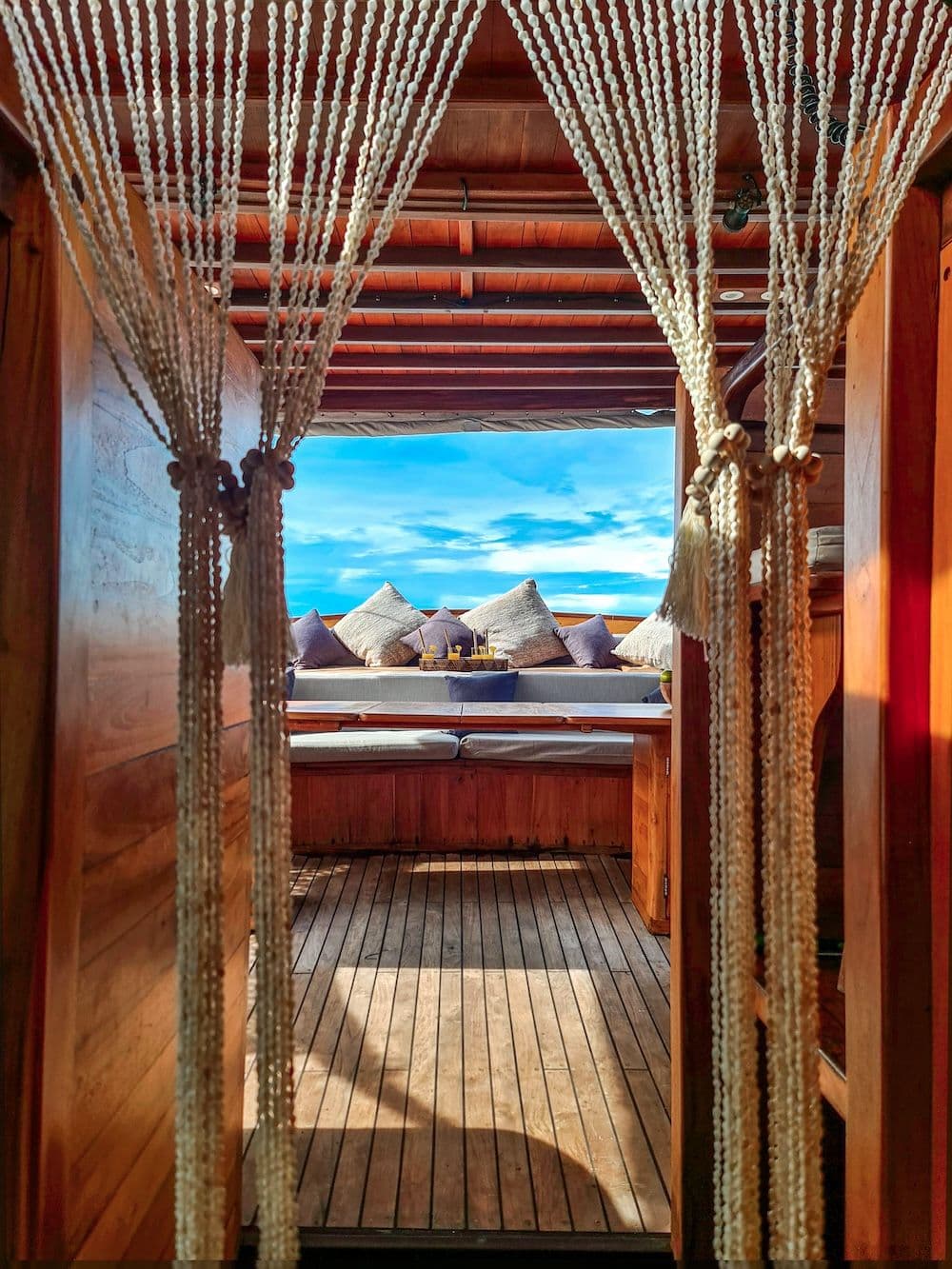 sofa on deck side, shell curtains, wooden interior, blue sky on the background