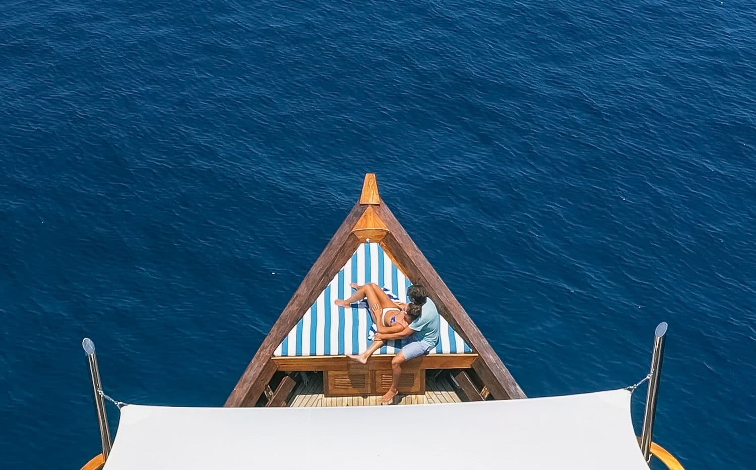 couple relaxing at front of rascal boat, blue sea water