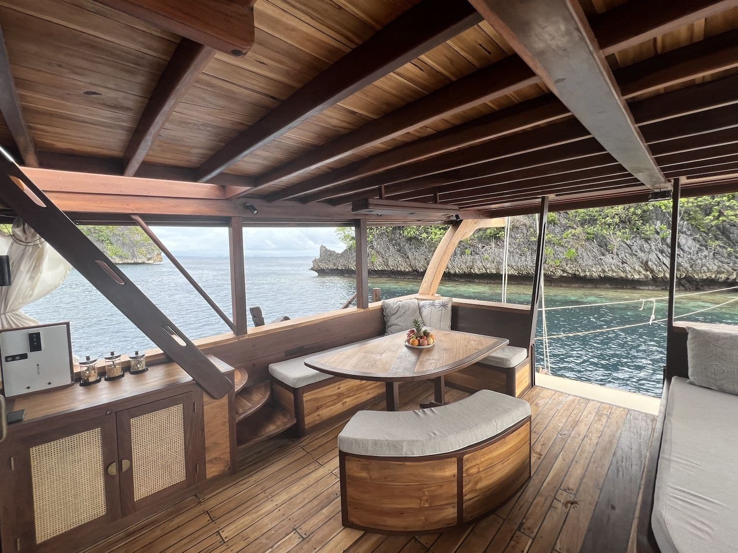 chill deck, wooden interior, island view, sea water, bright sky, wooden table, wooden stairs