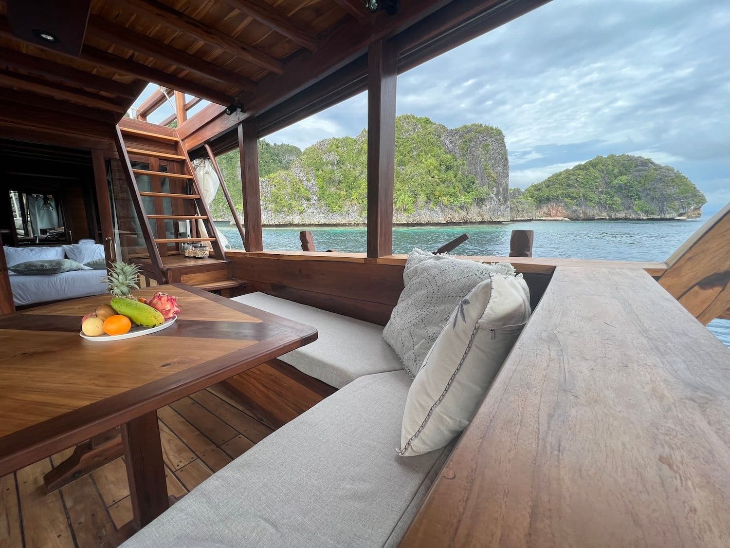 chill deck, wooden interior, wooden stairs, white sofa, table, island view, blue sky