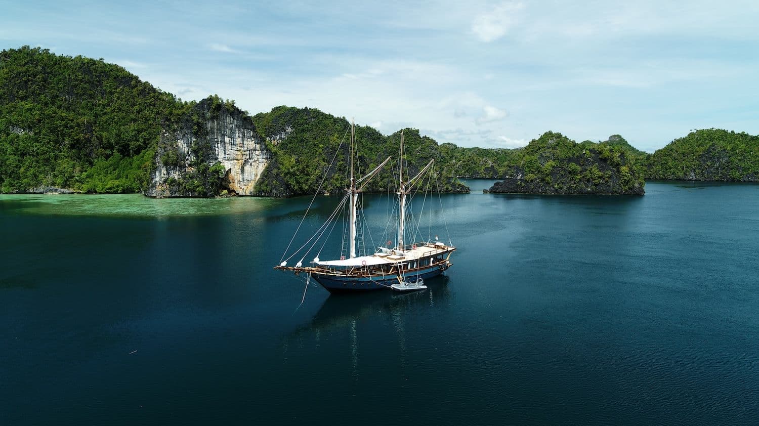 drone view of dewata boat, dark blue sea water, blue sky, island view