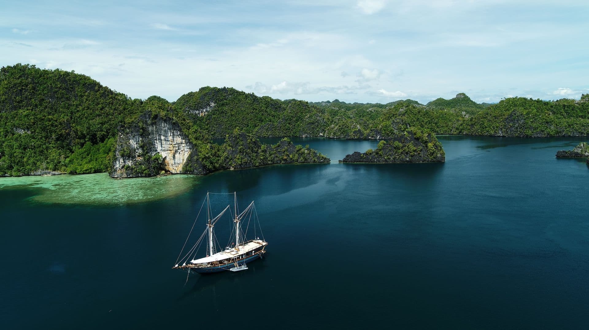 dewata boat, green hills, deep blue sea water, bright sky