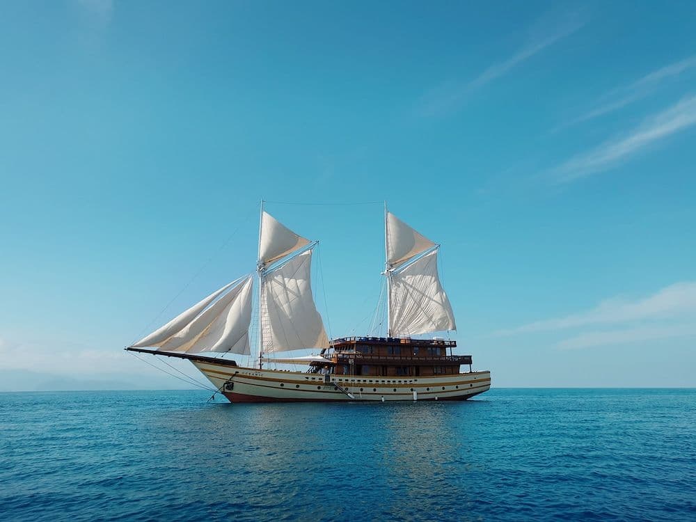 the maj oceanic boat landscape, white big sail, blue sky, blue sea water