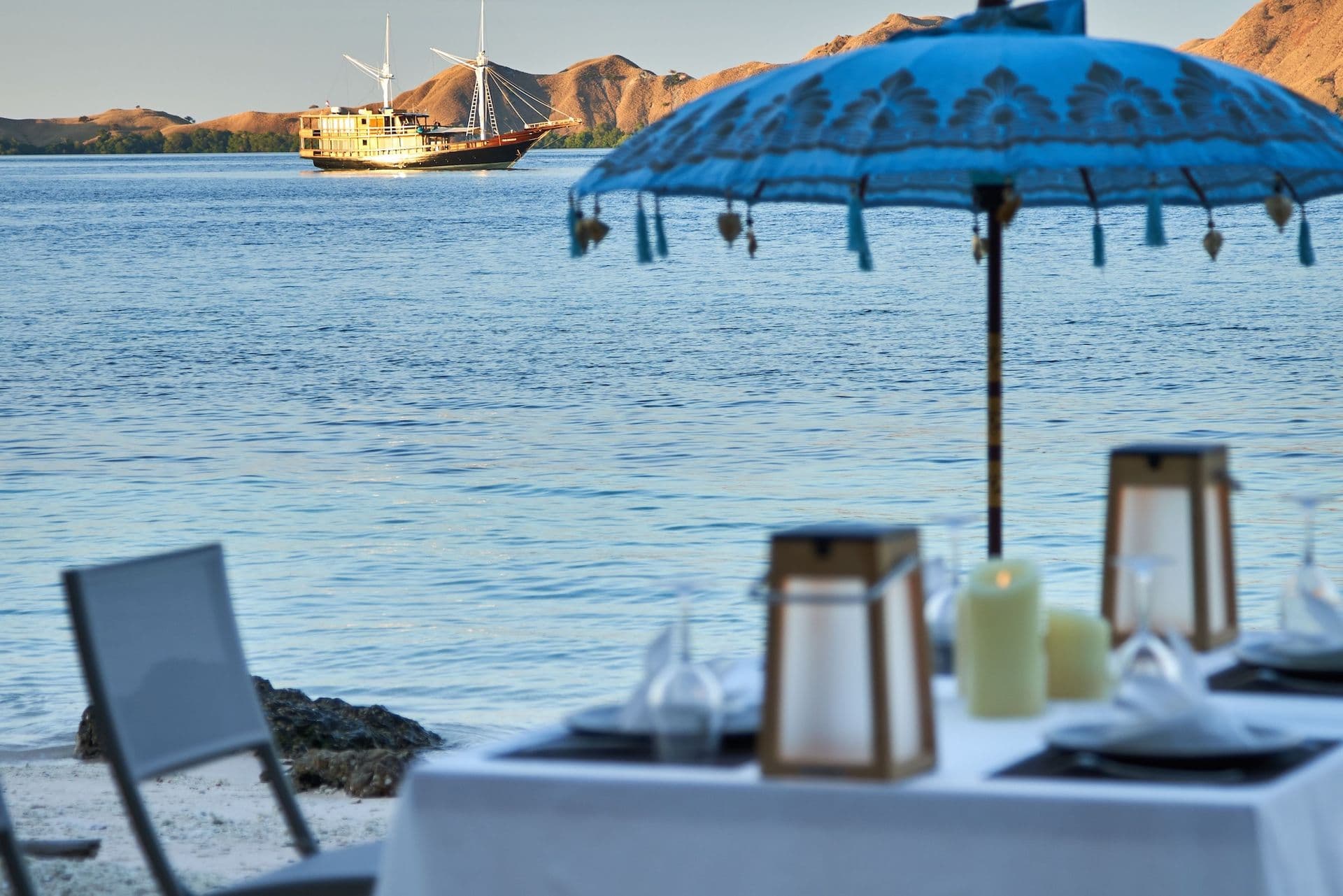 dining table setting, blue umbrella, oracle boat in the sunlight, glass, white table sheet