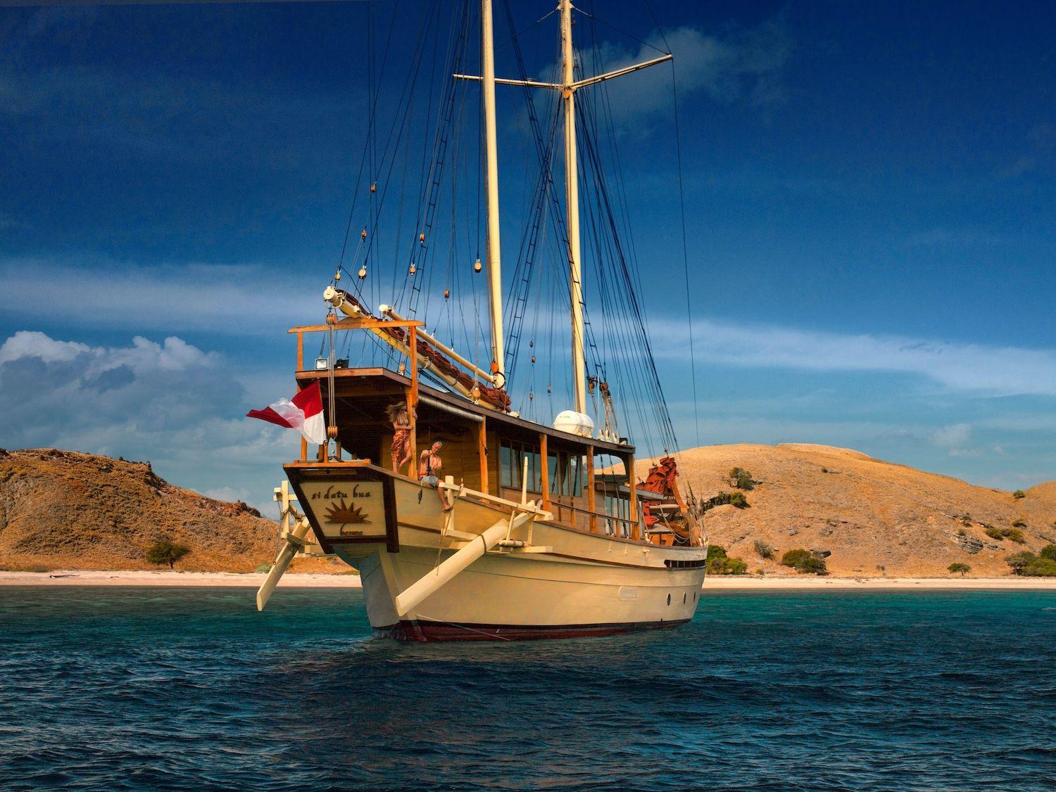 si datu bua boat with red sail, blue sky, blue sea water, panoramic view