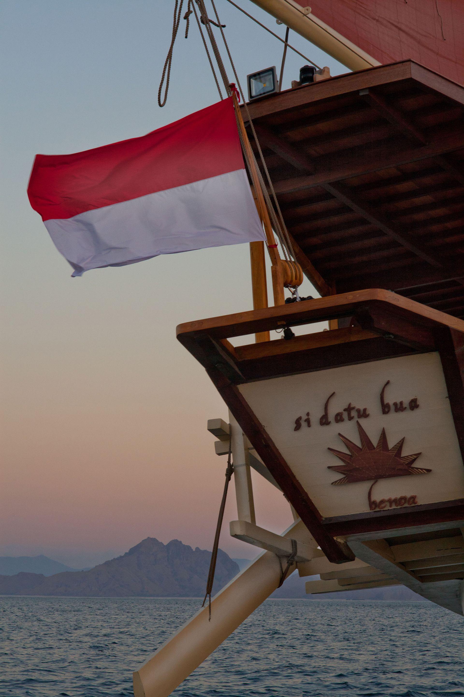 si datu bua boat with good panoramic view, orange sky, beautiful sea view, indonesia flag