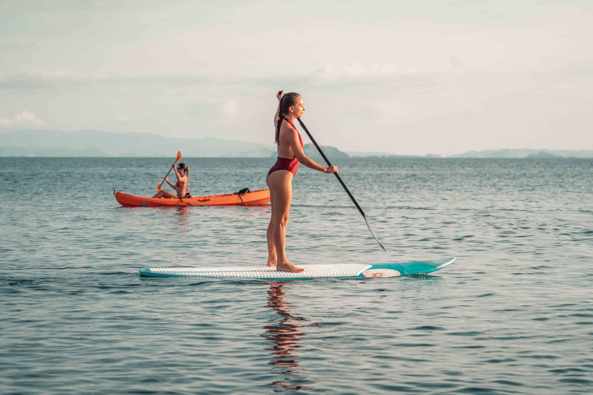 two girls play paddle boards together