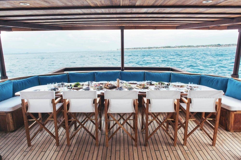 beautiful dining table at rascal boat, with blue pillows, view of blue sea water