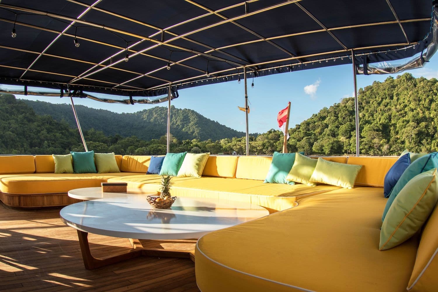 yellow sofa on the deck, indonesian flag, yellow and turquoise pillow, white round table