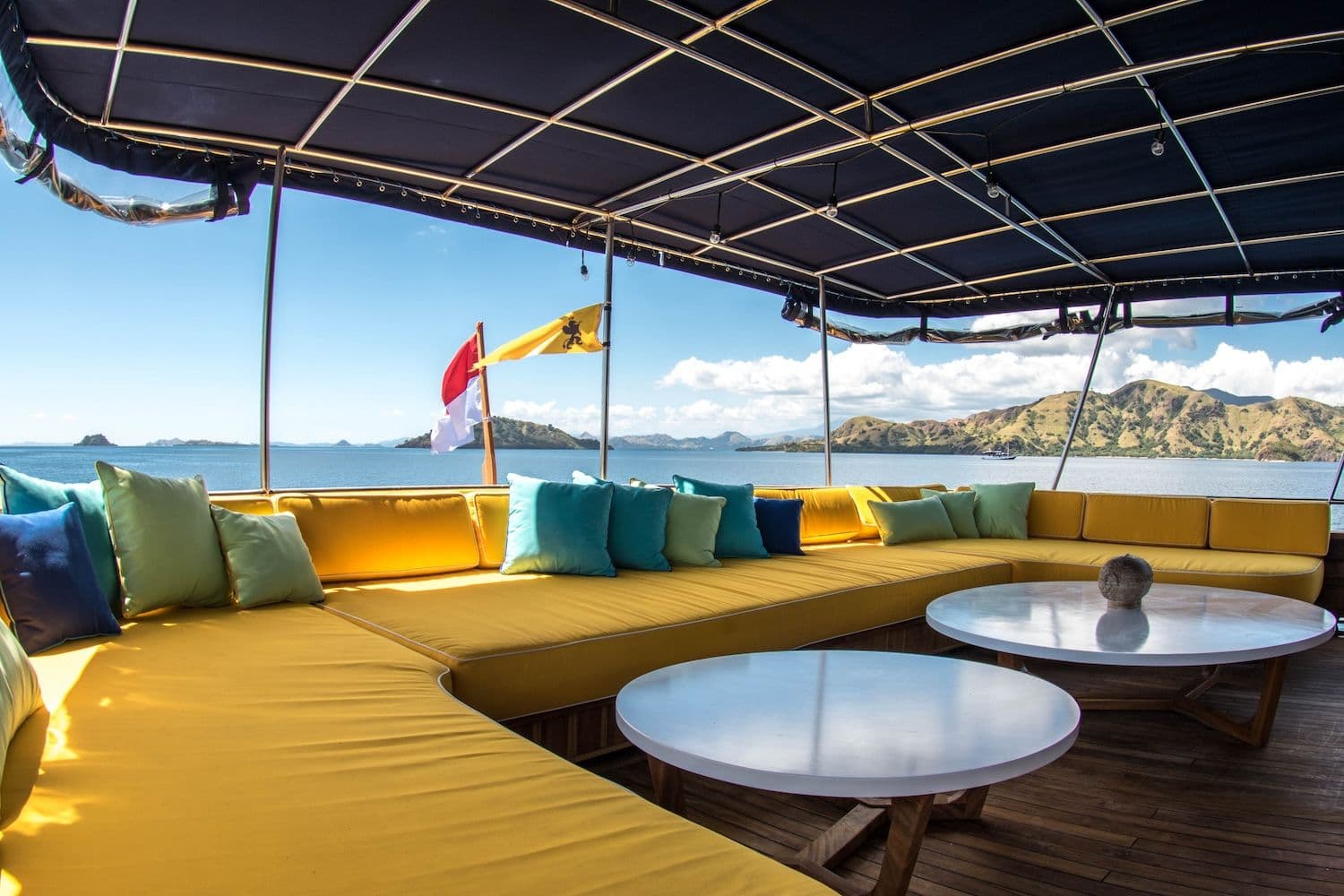 2 white round table at the center, indonesian flag, yellow sofa, turquoise and yellow pillow on the sofa