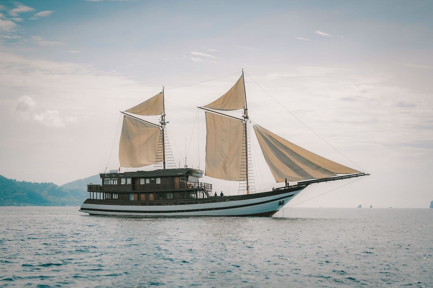 samsara samudra boat, white big sail, couldy atmoshphere, wooden boat exterior